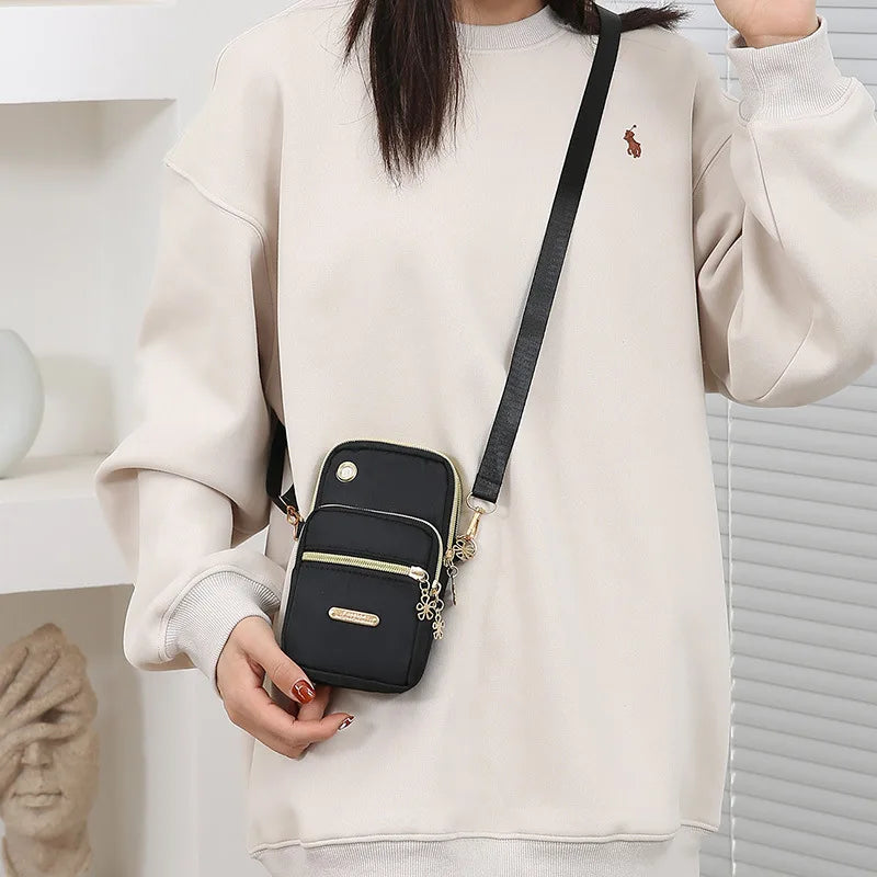 Compact crossbody bag with multiple zip pockets and adjustable strap